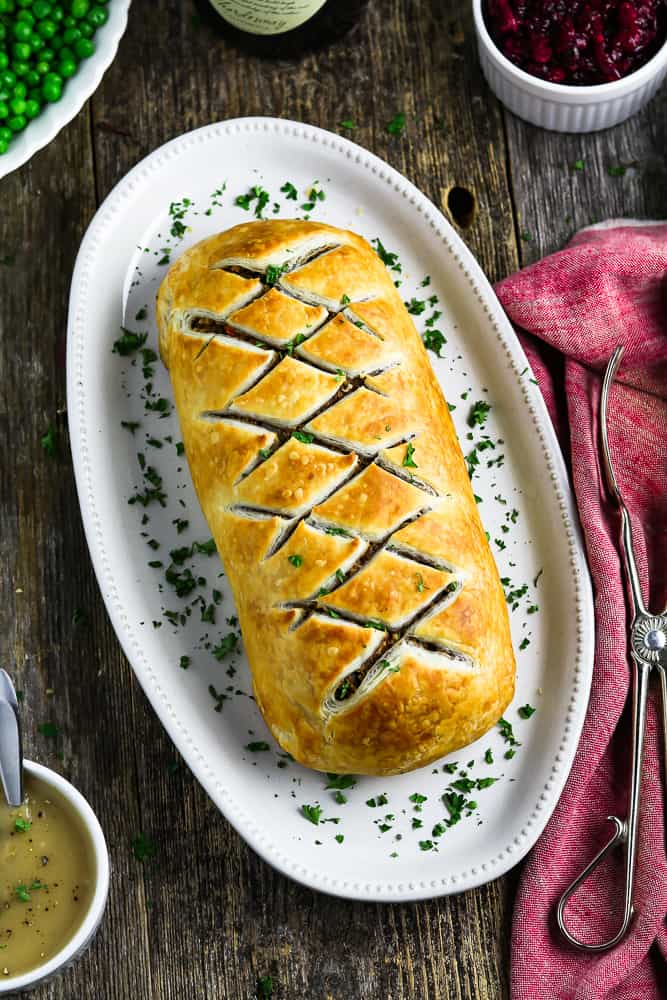 Overhead view of fully baked vegan wellington on a white serving platter. 