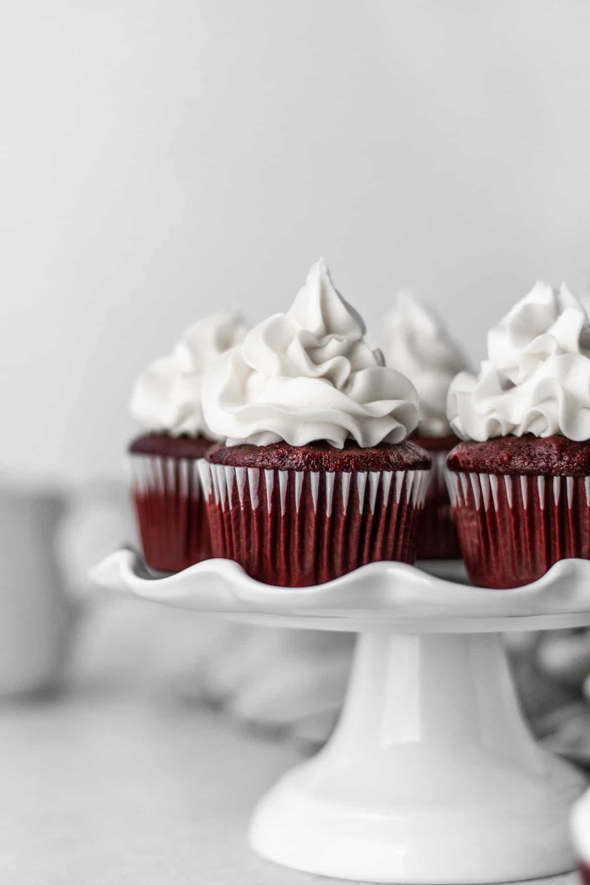 Batch of frosted vegan red velvet cupcakes on a cake stand.
