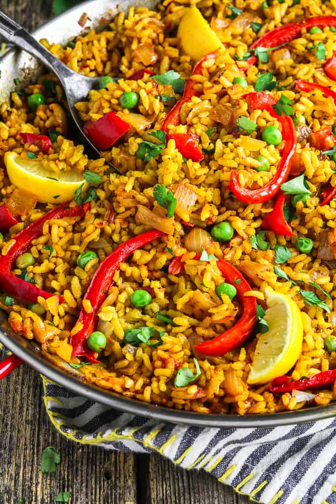 Close up view of vegan paella in a pan on top of a striped napkin. 