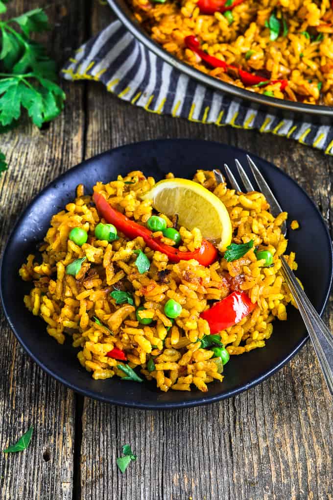 vegan paella on a black plate with a fork on the side. 