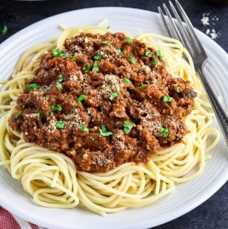 white plate topped with pasta and vegan bolognese sauce.