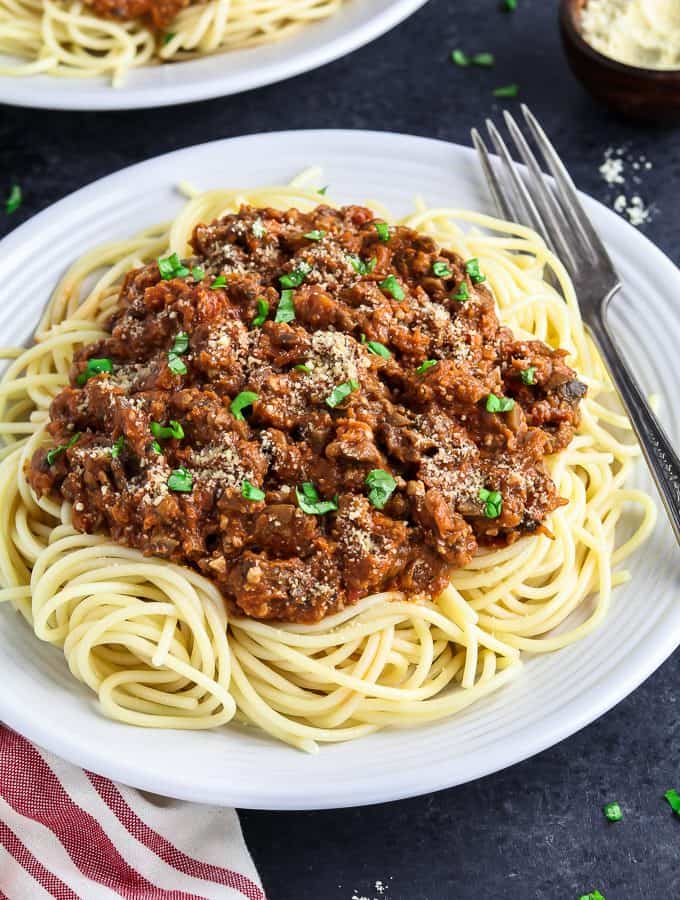 white plate topped with pasta and vegan bolognese sauce.