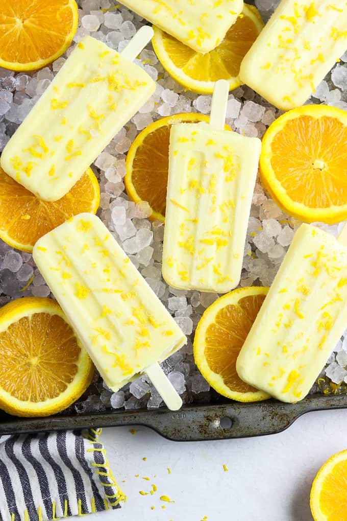 Orange creamsicle pops on a bed of ice and orange slices. 