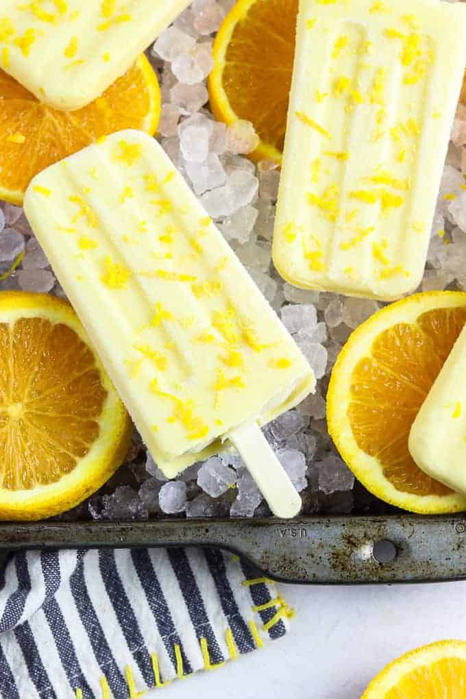 creamsicle popsicles in a pan with ice and sliced oranges. 