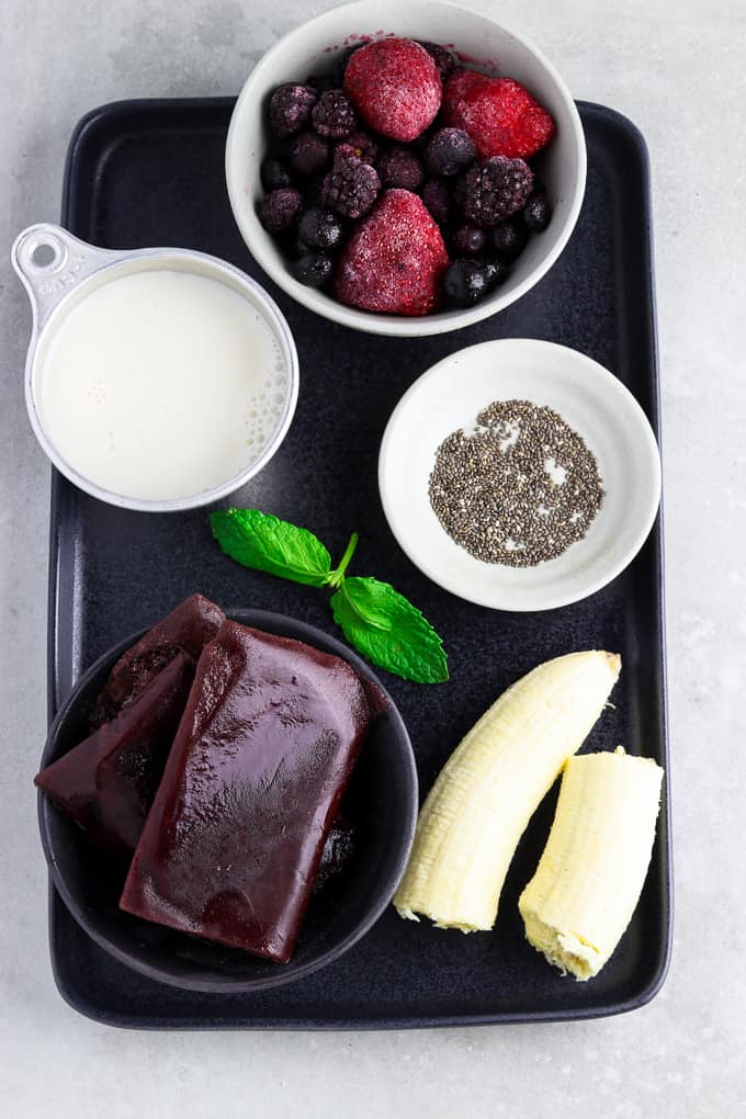 Ingredients on a black tray for acai bowl recipe. 
