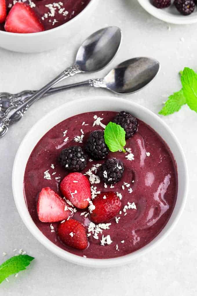 Overhead view of two acai bowls with spoons in the middle.