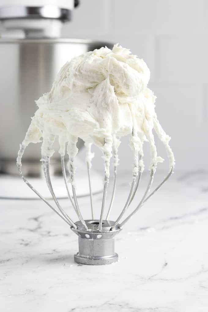 Whisk attachment covered in whipped frosting. 