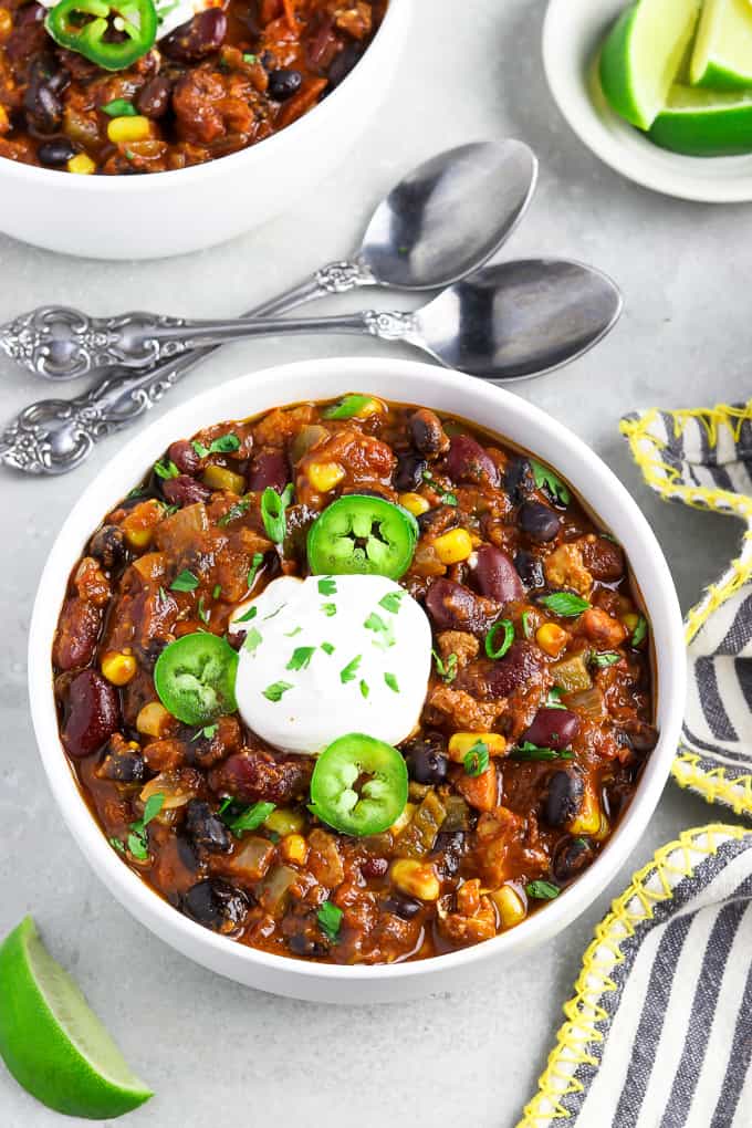 overhead view of two bowls of vegan chili topped with jalapeños and vegan sour cream. 