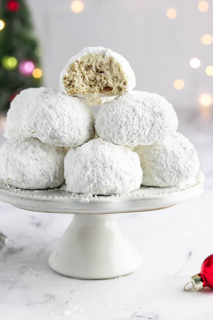 Stack of vegan snowball cookies on a stand with one cookie cut in half.