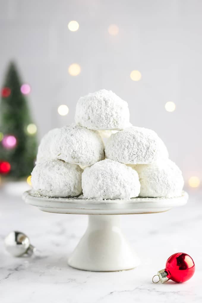 A stack of vegan snowball cookies on a stand with lights in the background. 