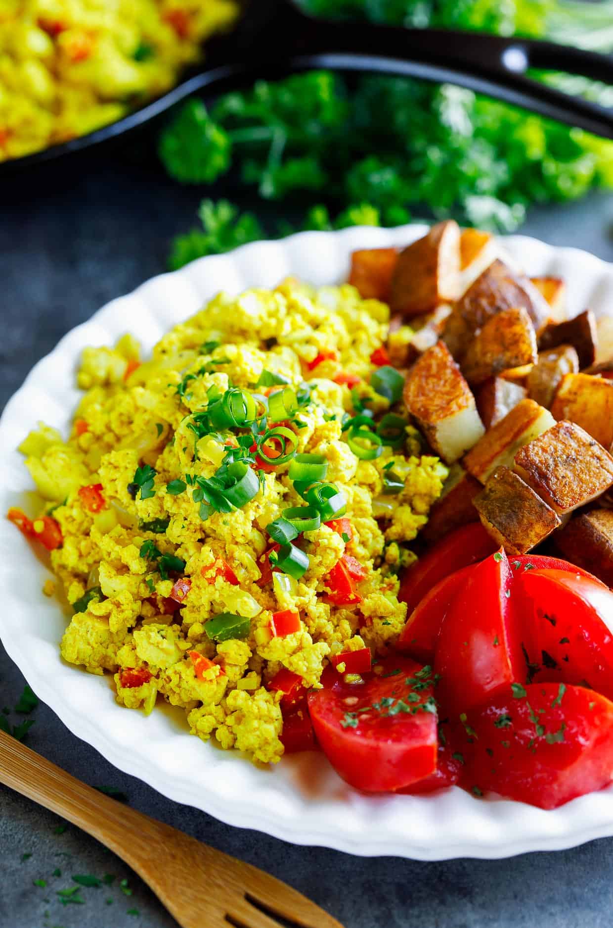 tofu scramble on a plate with tomatoes on the side.