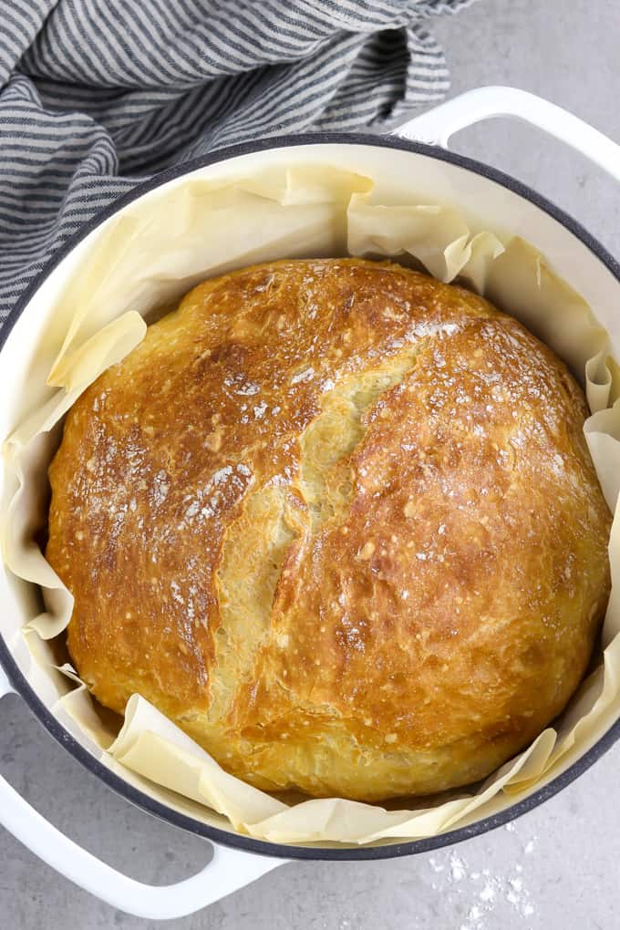 overhead view of no knead artisan bread in a white pot with napkin on the side. 