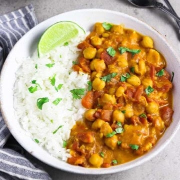 a bowl of vegan chickpea curry with rice on the side.