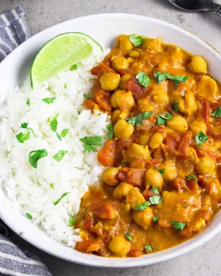 a bowl of vegan chickpea curry with rice on the side.