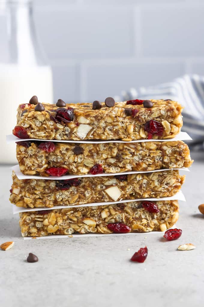 4 vegan granola bars stacked on top of each other. Striped napkin and bottled milk in the background. 