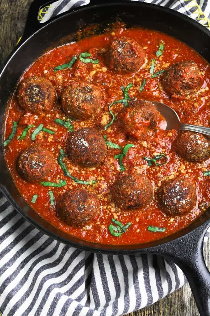 Vegan meatballs and sauce in a cast iron skillet. Striped napkin on the side. 