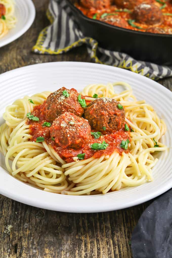 Side view of a plate of spaghetti topped with meatless balls and sauce. 