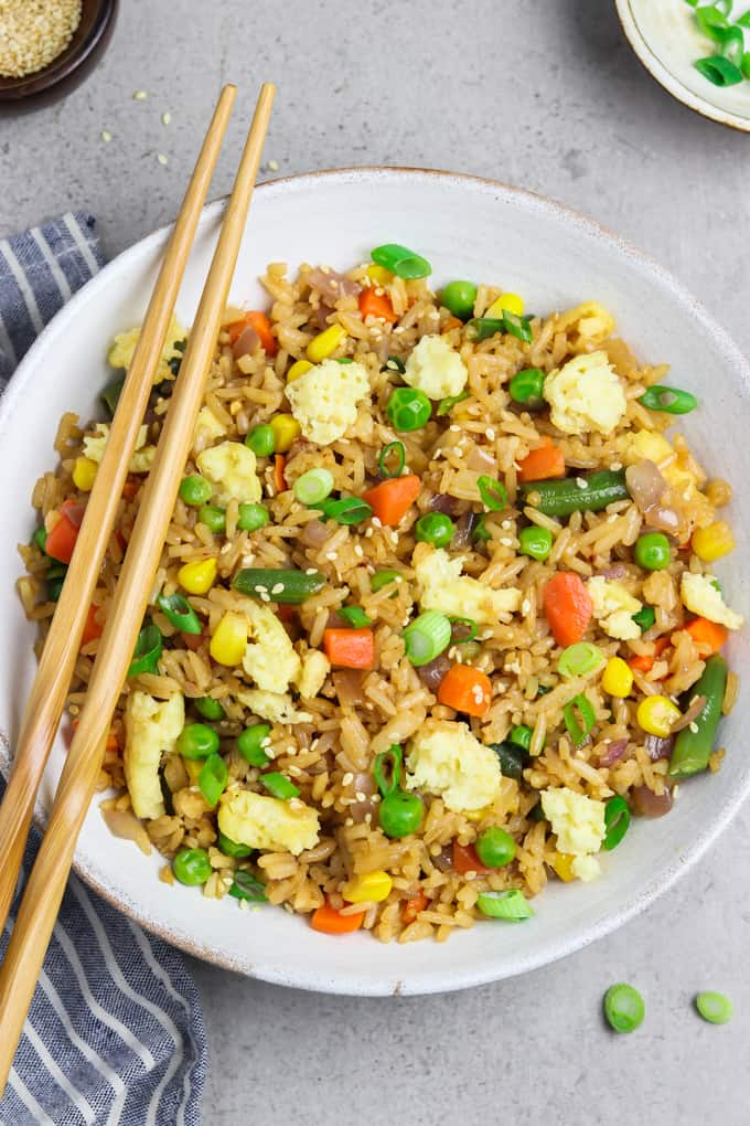 Overhead view of vegan fried rice in a bowl with chopsticks on the side. 