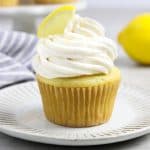 vegan lemon cupcake on a white plate. Fresh lemon in the background.