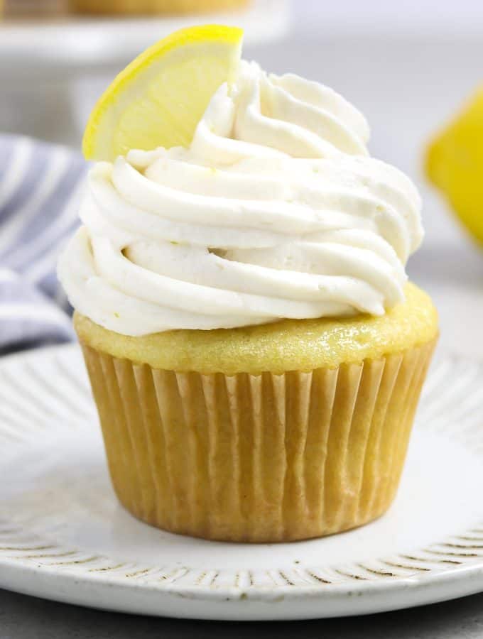 vegan lemon cupcake on a white plate. Fresh lemon in the background.