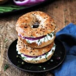 two bagels with cream cheese stacked on top of each other.