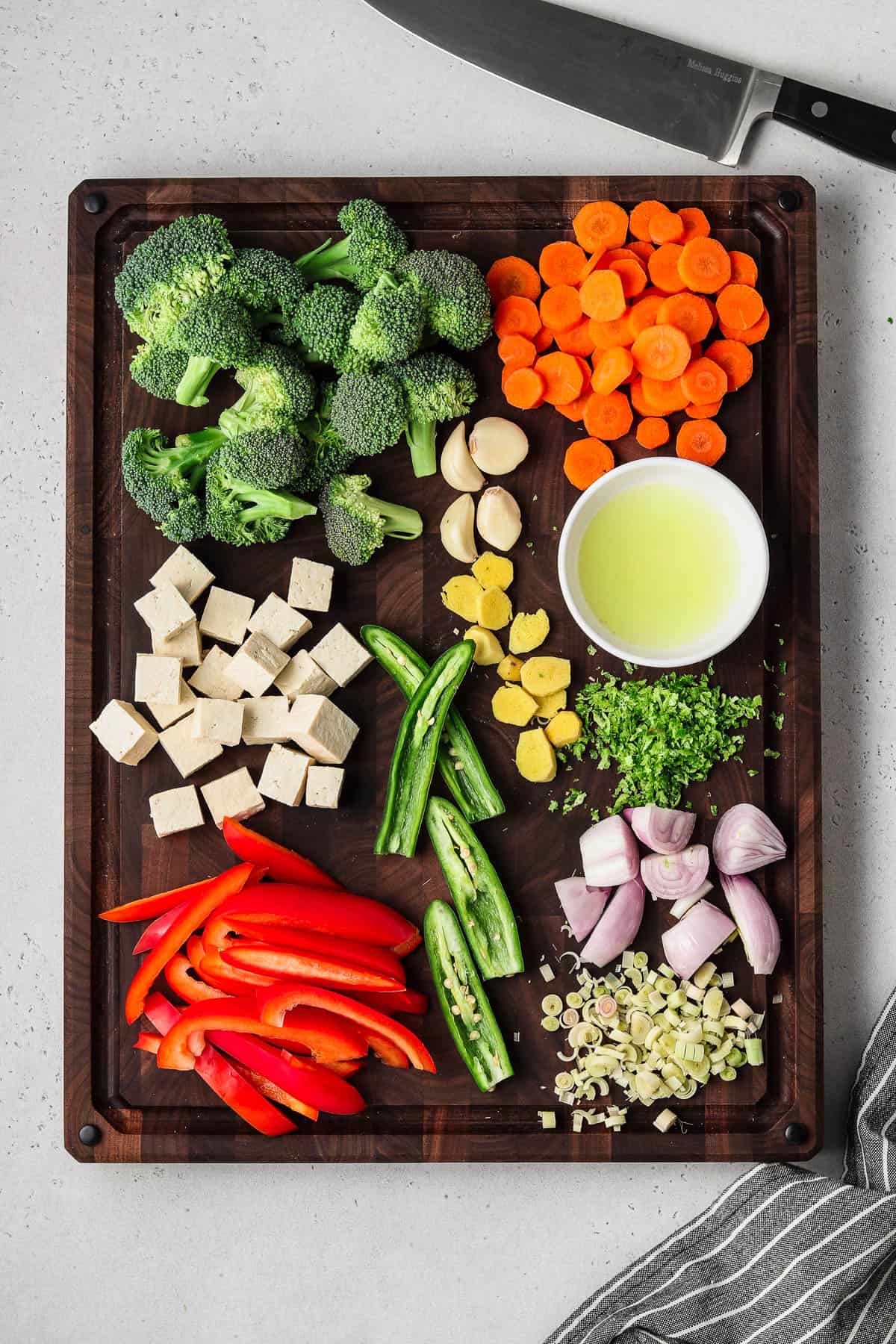 Cut vegetables on a wood cutting board with a napkin on the side. 