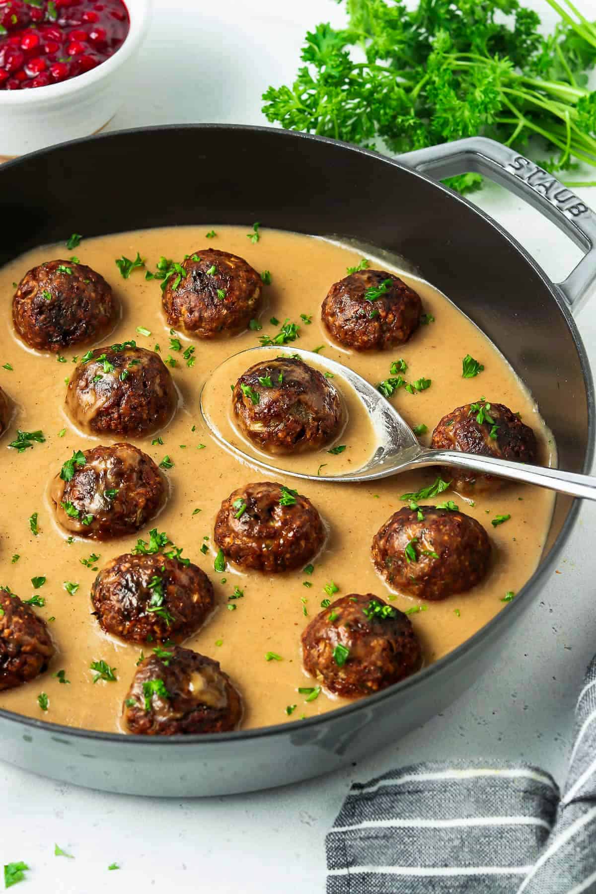 Sideview of vegan swedish meatballs in gravy with parsley on top.