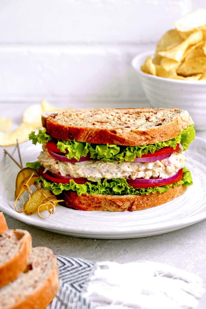 sandwich on a plate with chips in the background.