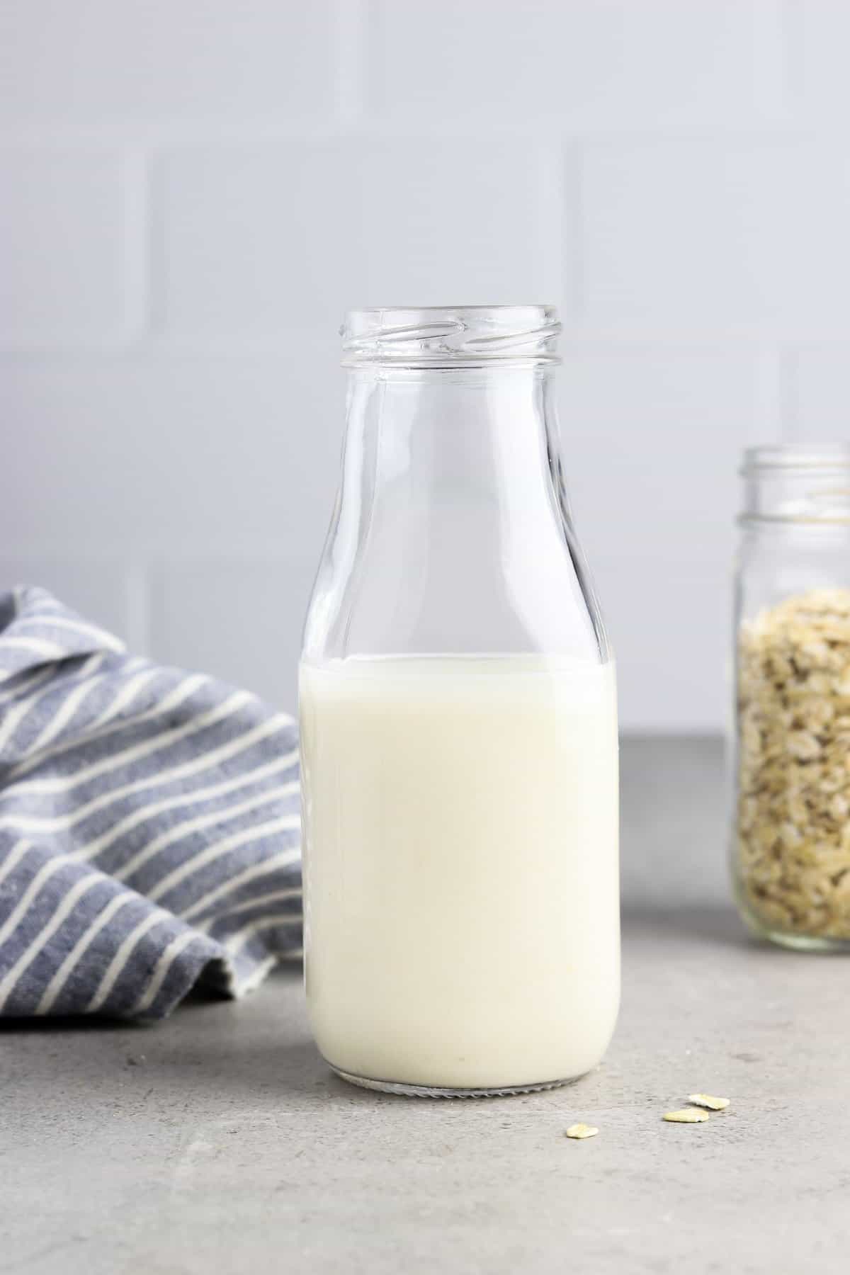 Oat milk in a bottle with a jar of oats in the background. 