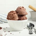 chocolate ice cream in a white bowl with spoons on side.