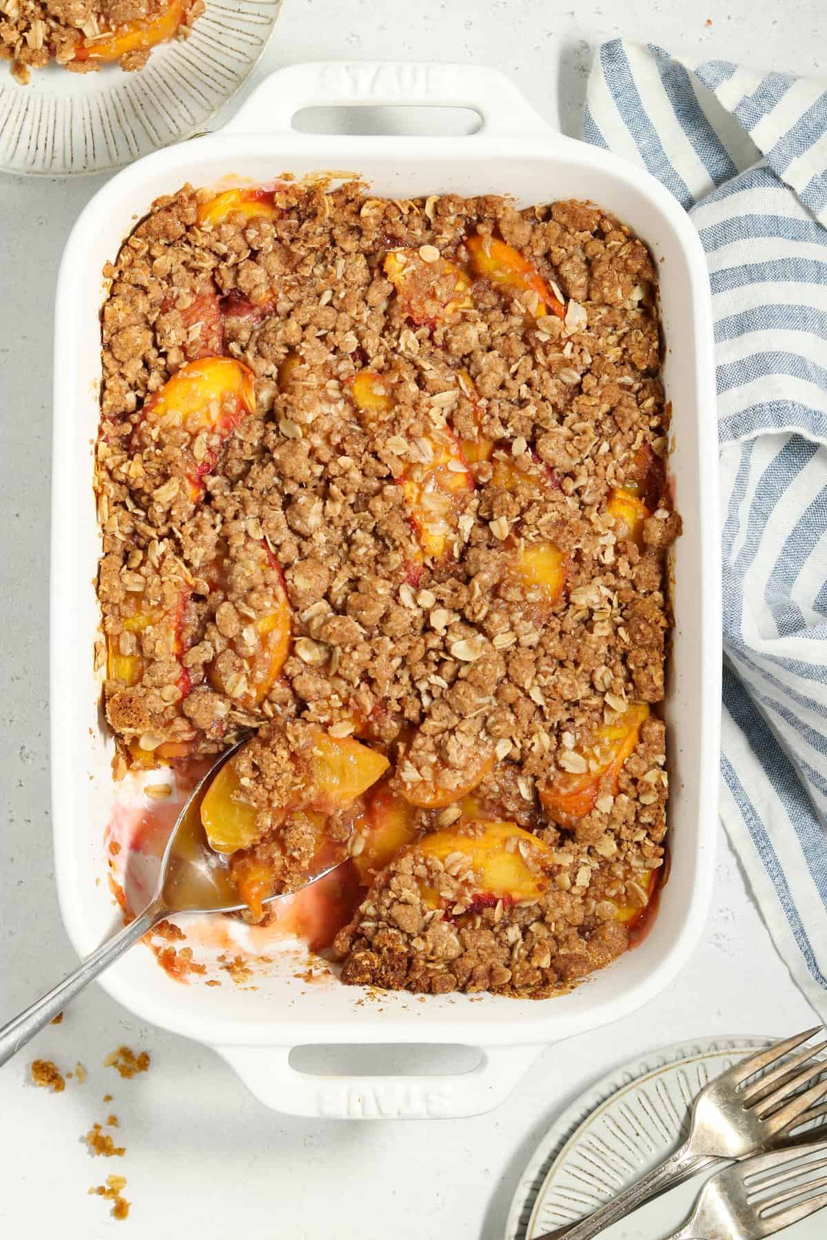 Overhead view of fully baked vegan peach crisp in a white casserole dish.