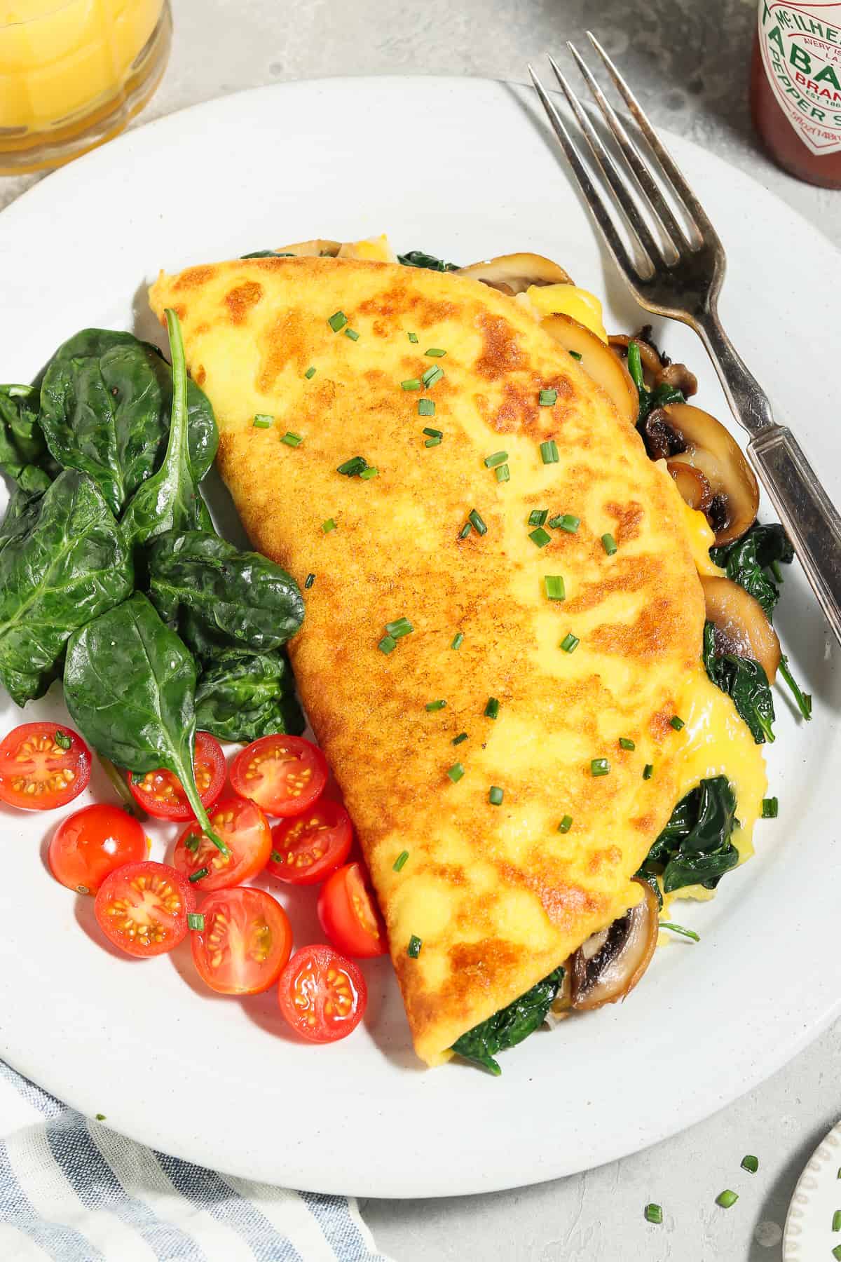 Fully cooked and assembled JUST Egg omelette with tomatoes and spinach on the side. 