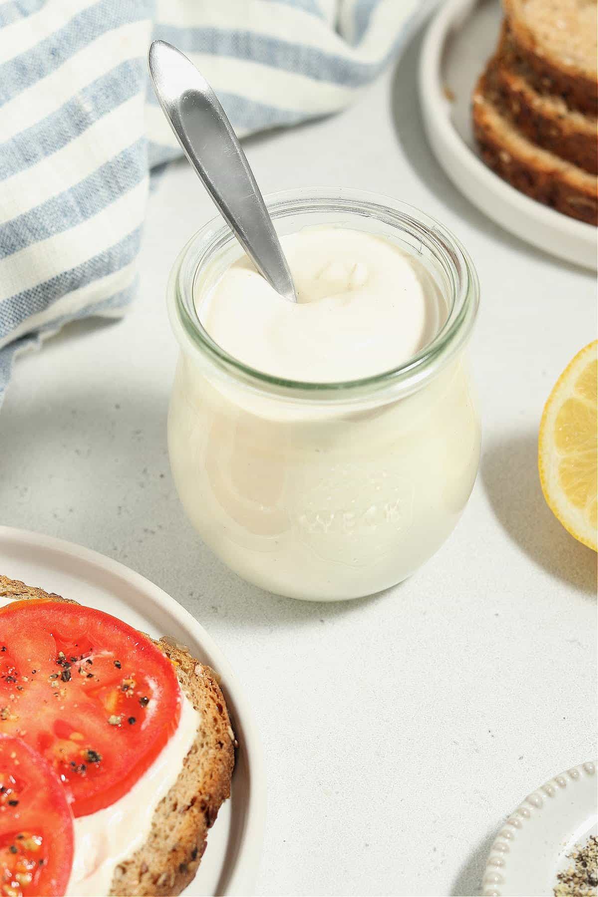 Close up view of vegan mayo in a jar with a spoon sticking out. 