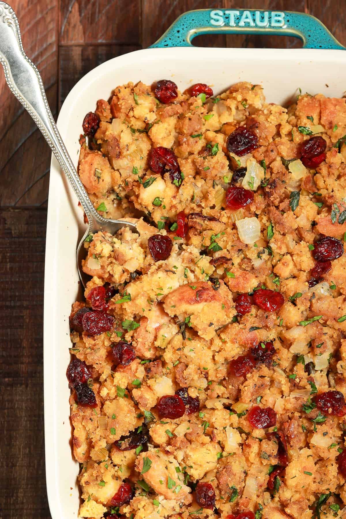 Close up view of vegan cornbread stuffing in a casserole dish with spoon inside. 