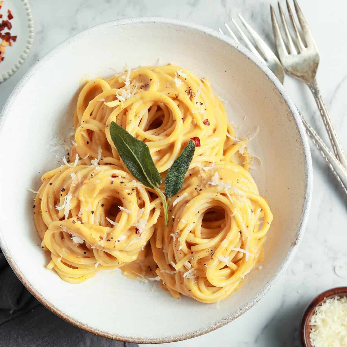 Overhead shot of butternut squash pasta in a white bowl, topped with sage