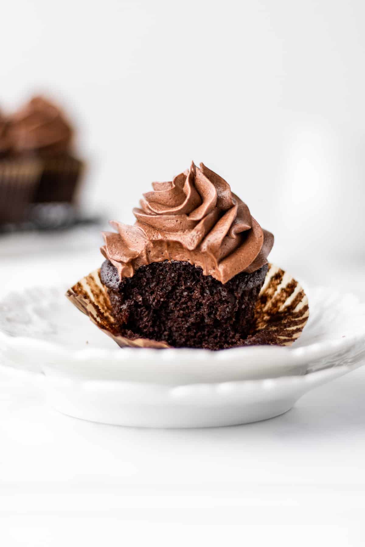 Close up view of a vegan chocolate cupcake on a white plate. 