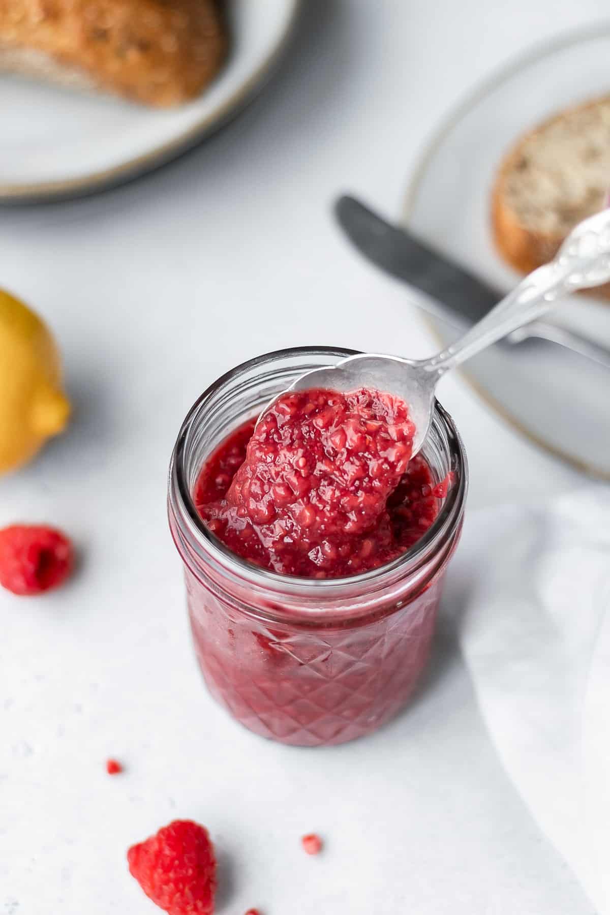 Spooning out chia seed jam from a jar with a spoon.