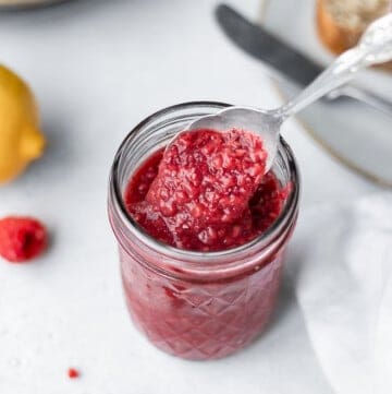 Raspberry chia seed jam in a glass jar with a spoon inside
