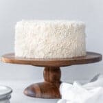 front view of coconut cake on a wood cake stand