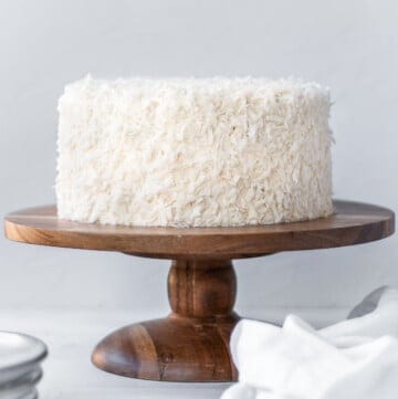 front view of coconut cake on a wood cake stand