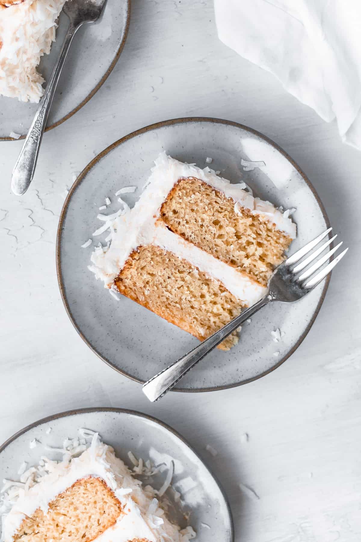 Overhead view showing 3 slices of vegan coconut cake on plate with forks on the side. 