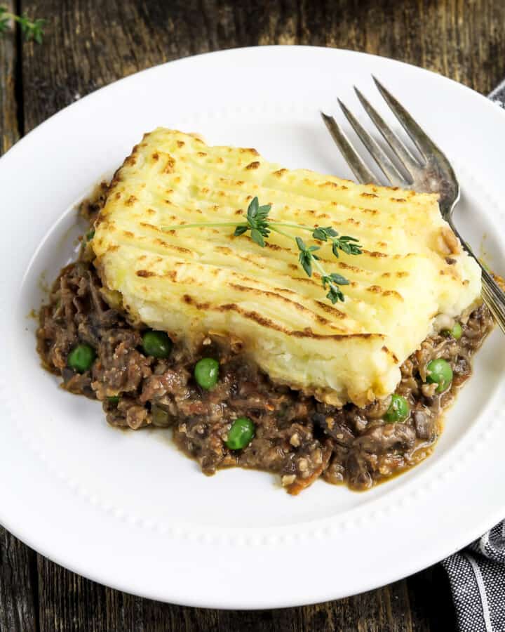 a piece of shepherd's pie on a plate with a fork and napkin on the side.