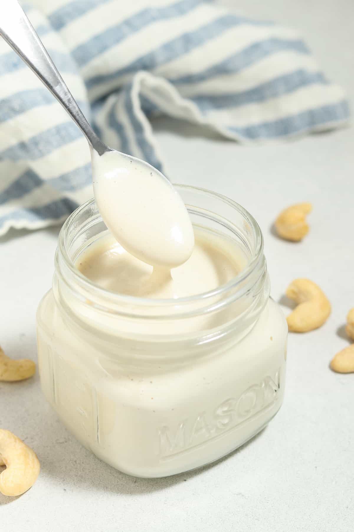 Pulling a spoon out of a jar of cashew cream.