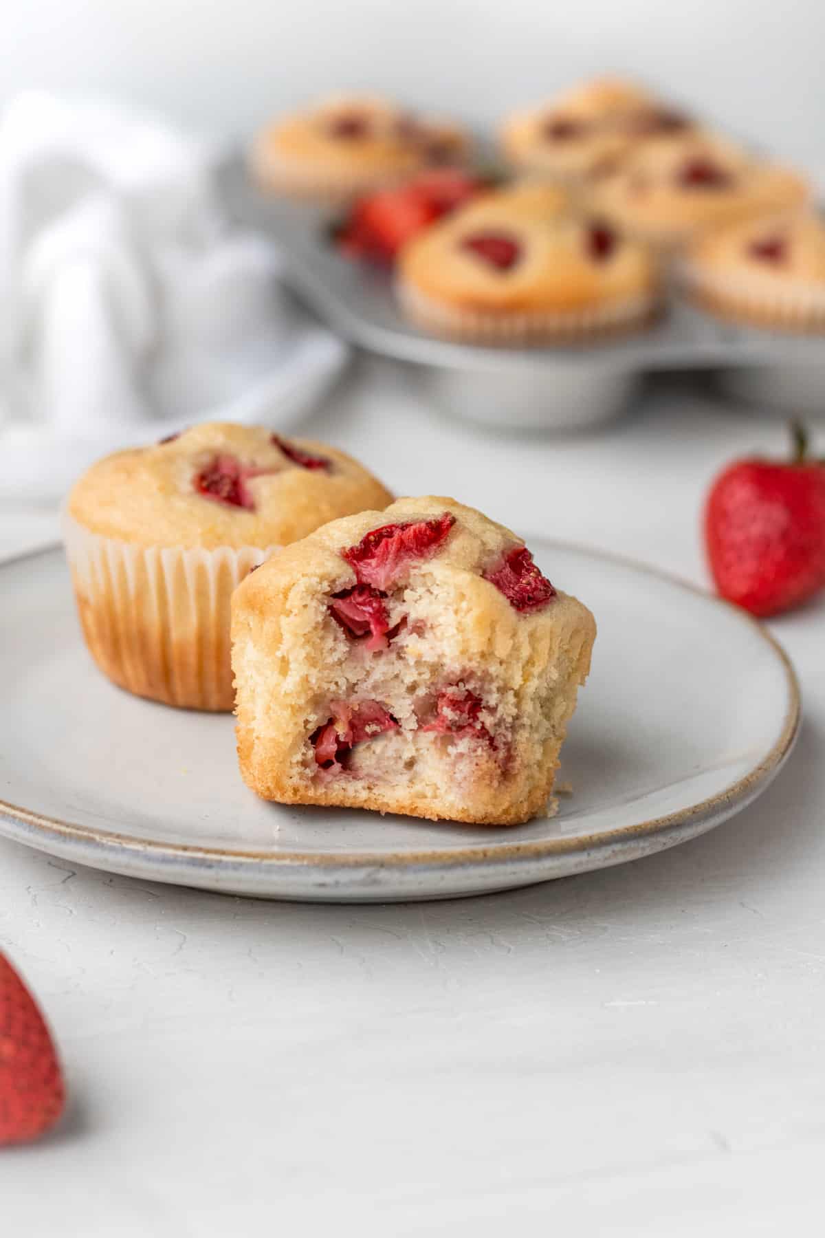 Two fully baked vegan strawberry muffins on a white plate. 
