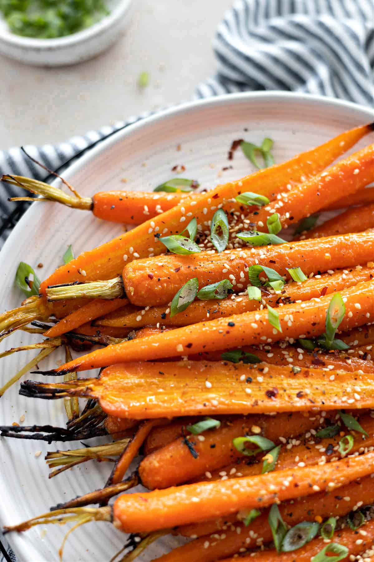 Side view of miso glazed carrots on a white plate. 