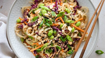 peanut noodle salad in a bowl with chopsticks on the side.