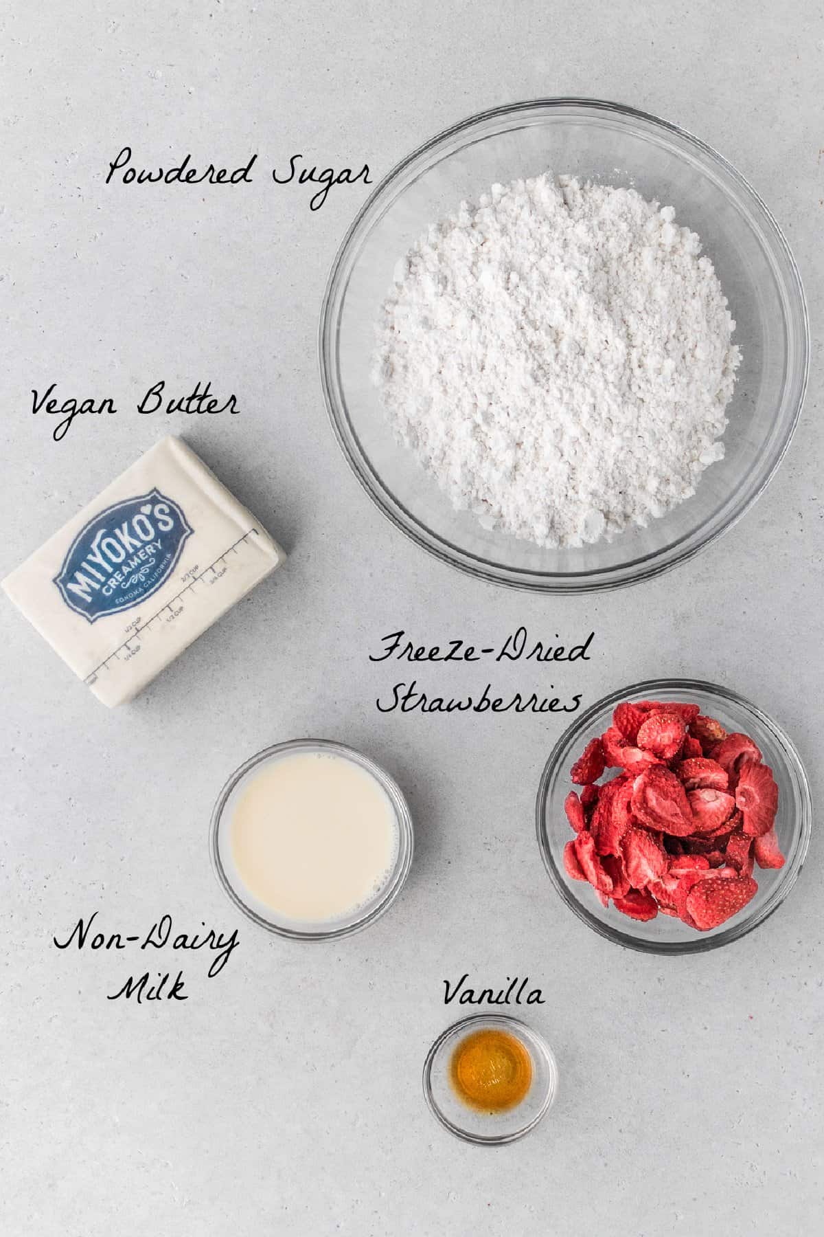 Ingredients to make strawberry frosting on a stone table top. 