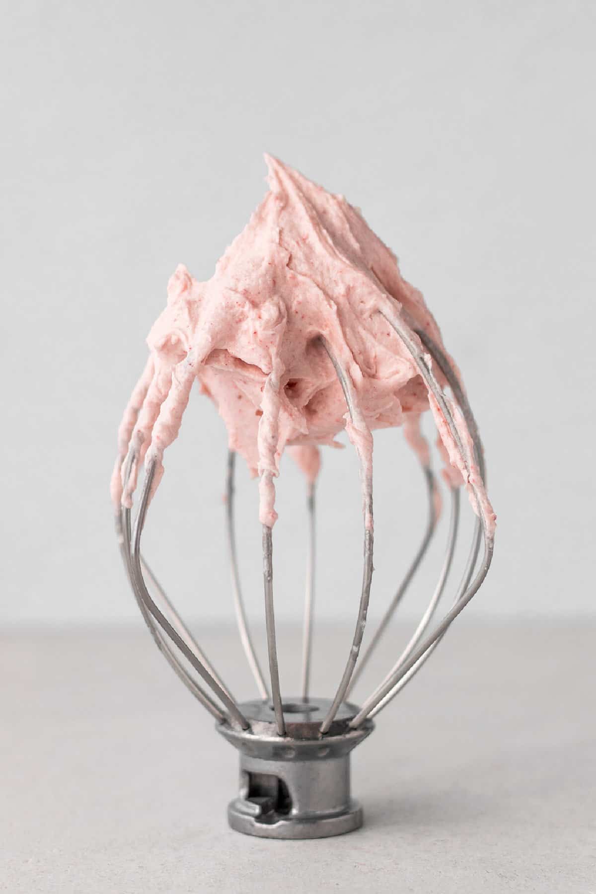 Vegan strawberry frosting on a balloon whisk attachment. 
