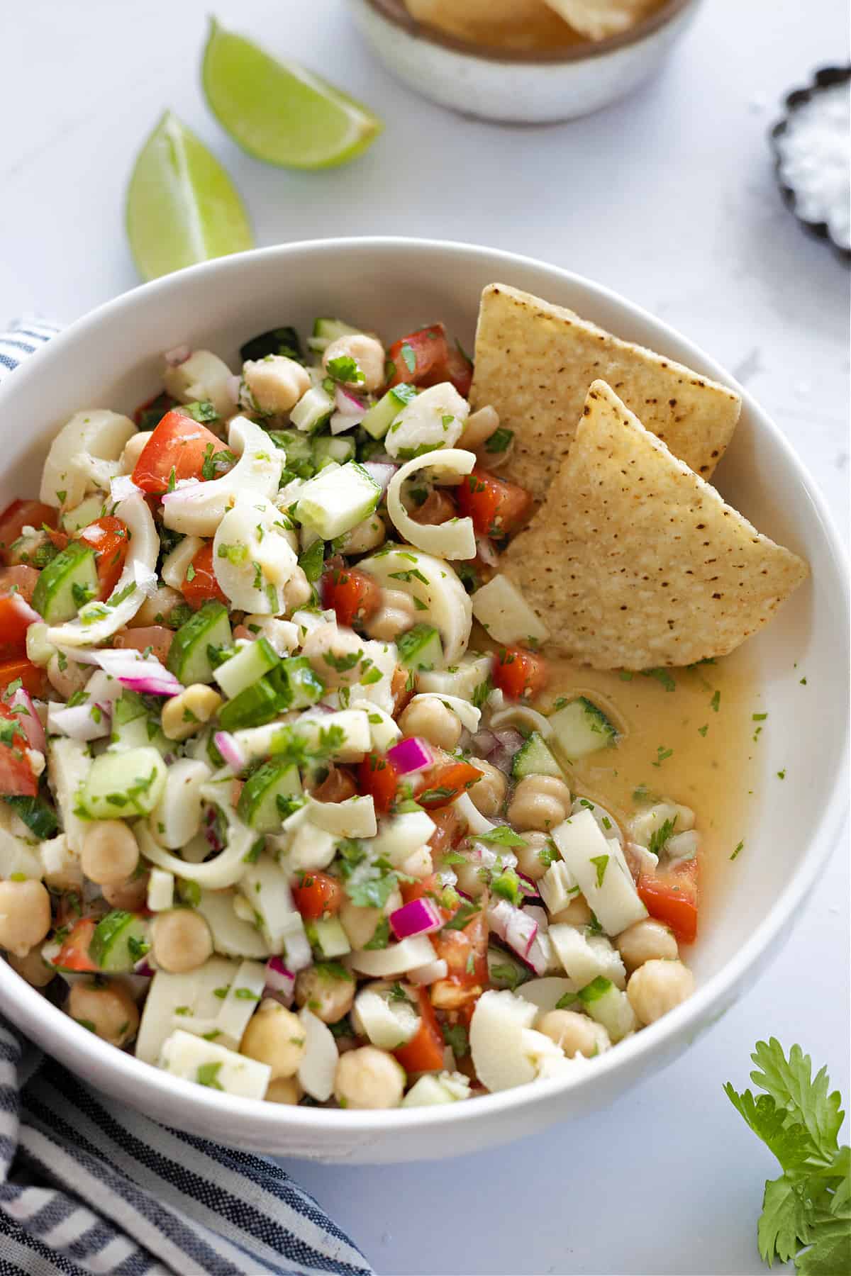 Closeup view of vegan ceviche in a white bowl with tortilla chips on the side. 