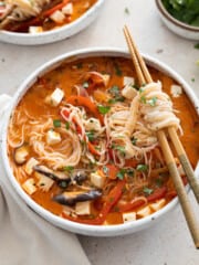 Thai red curry noodle soup in a white bowl.